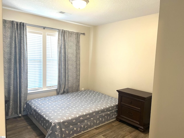 bedroom with dark hardwood / wood-style floors and a textured ceiling