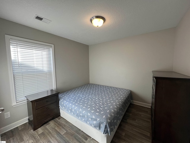 bedroom with dark hardwood / wood-style floors and a textured ceiling