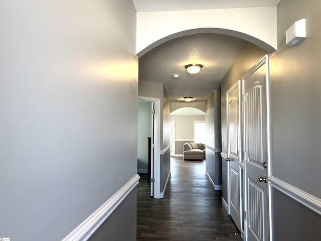 corridor with dark hardwood / wood-style flooring and a textured ceiling