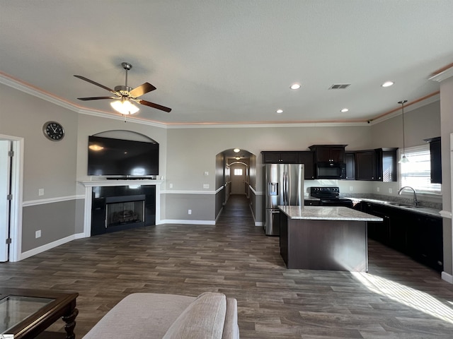 kitchen with ornamental molding, black appliances, decorative light fixtures, a center island, and a tiled fireplace