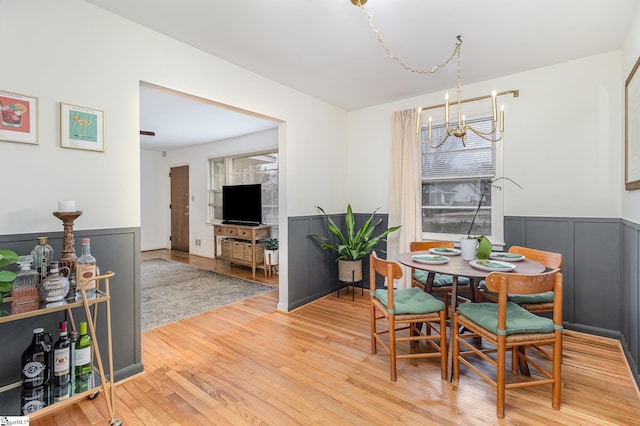 dining space with hardwood / wood-style floors and a notable chandelier