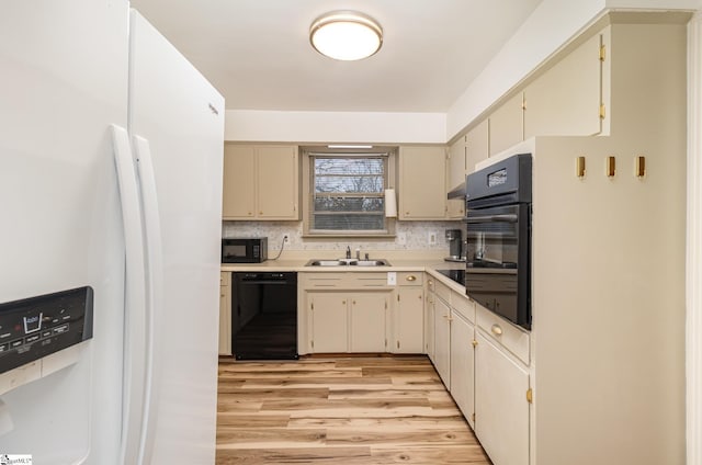 kitchen featuring tasteful backsplash, sink, black appliances, light hardwood / wood-style flooring, and cream cabinetry