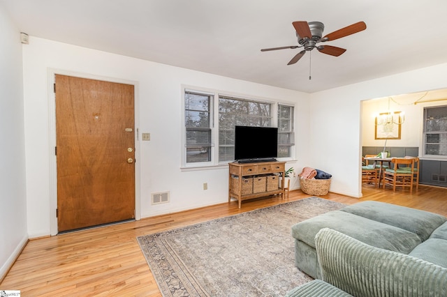 living room with wood-type flooring and ceiling fan with notable chandelier