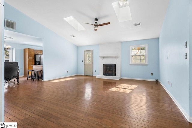 unfurnished living room with a fireplace, ceiling fan, dark hardwood / wood-style flooring, and lofted ceiling with skylight