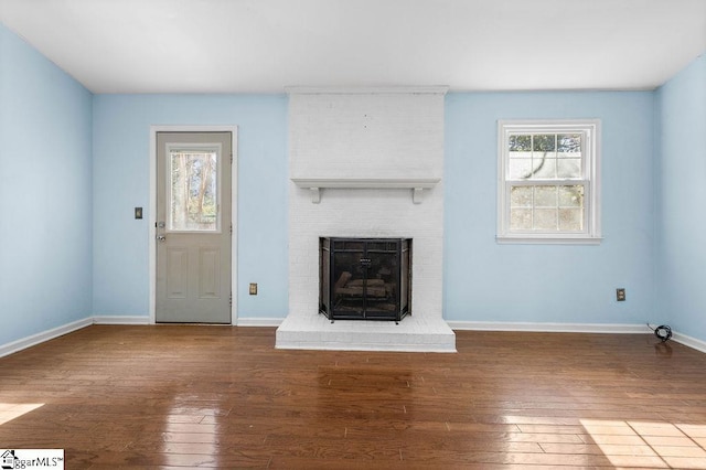 unfurnished living room with a fireplace, dark wood-type flooring, and plenty of natural light