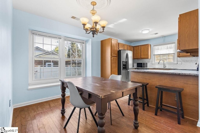 dining room with dark hardwood / wood-style flooring, plenty of natural light, a notable chandelier, and sink