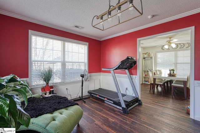 workout area with ceiling fan, dark wood-type flooring, a textured ceiling, and ornamental molding