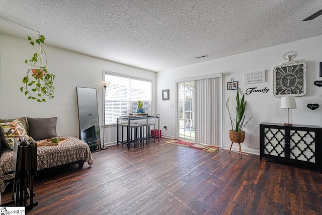 sitting room with dark hardwood / wood-style flooring, a textured ceiling, and ceiling fan