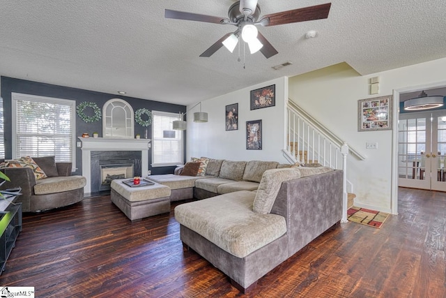 living room featuring ceiling fan, dark hardwood / wood-style flooring, and a textured ceiling