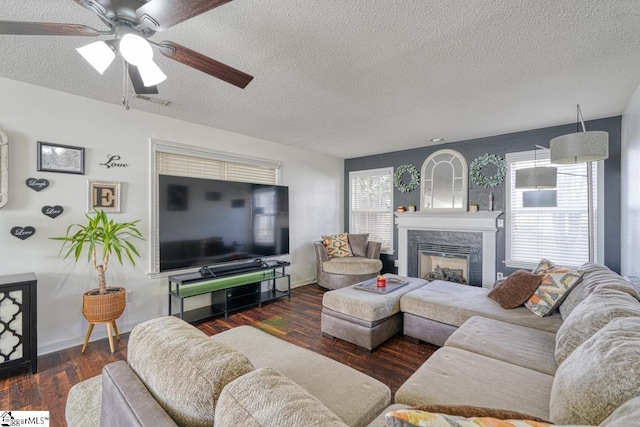 living room featuring dark hardwood / wood-style flooring, ceiling fan, a fireplace, and a textured ceiling