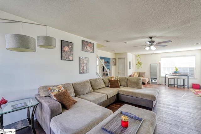 living room with a textured ceiling, hardwood / wood-style flooring, and ceiling fan