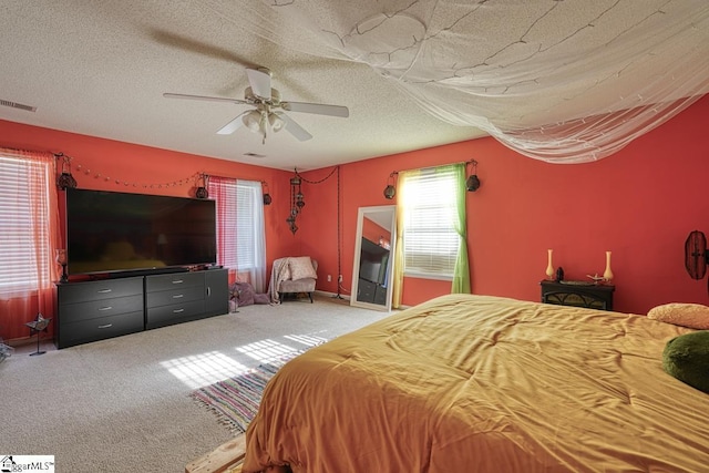 bedroom with a textured ceiling, carpet floors, and ceiling fan