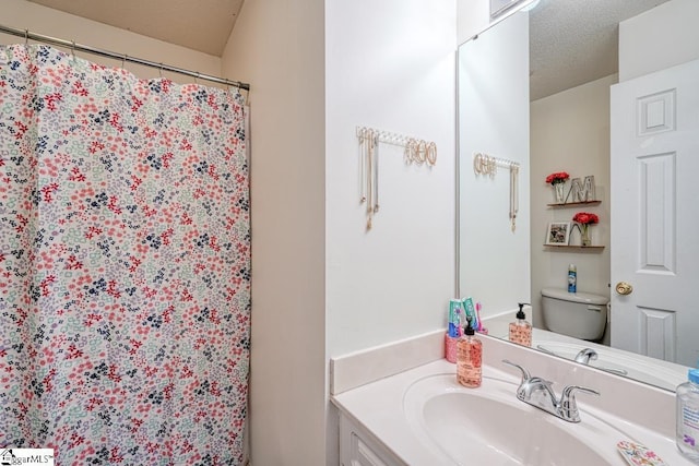 bathroom featuring vanity, toilet, a textured ceiling, and walk in shower