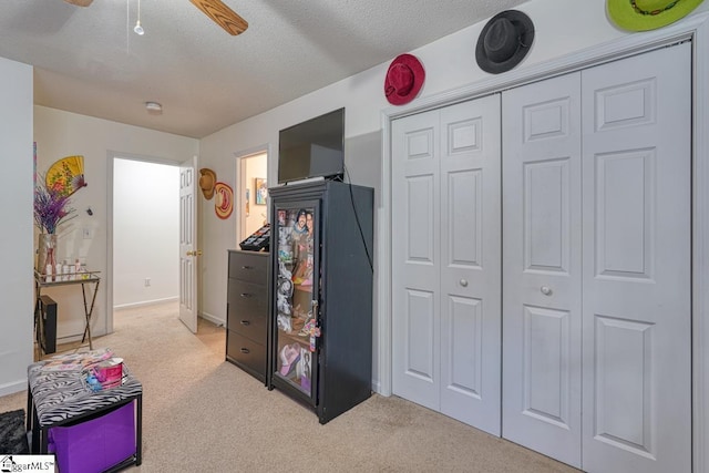 interior space featuring a textured ceiling, light colored carpet, and ceiling fan