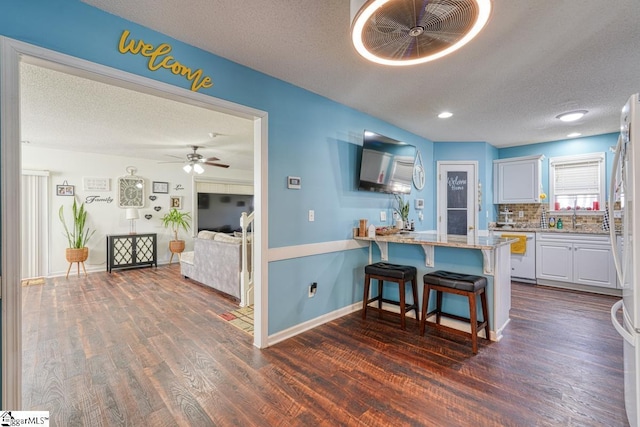 kitchen featuring white cabinets, a textured ceiling, tasteful backsplash, kitchen peninsula, and a breakfast bar area