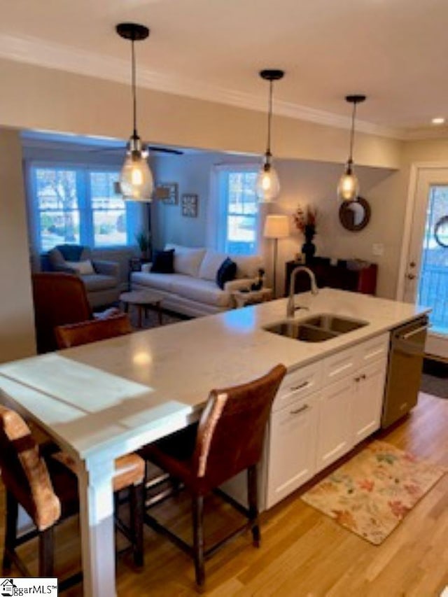 kitchen featuring a kitchen bar, white cabinetry, sink, and hanging light fixtures