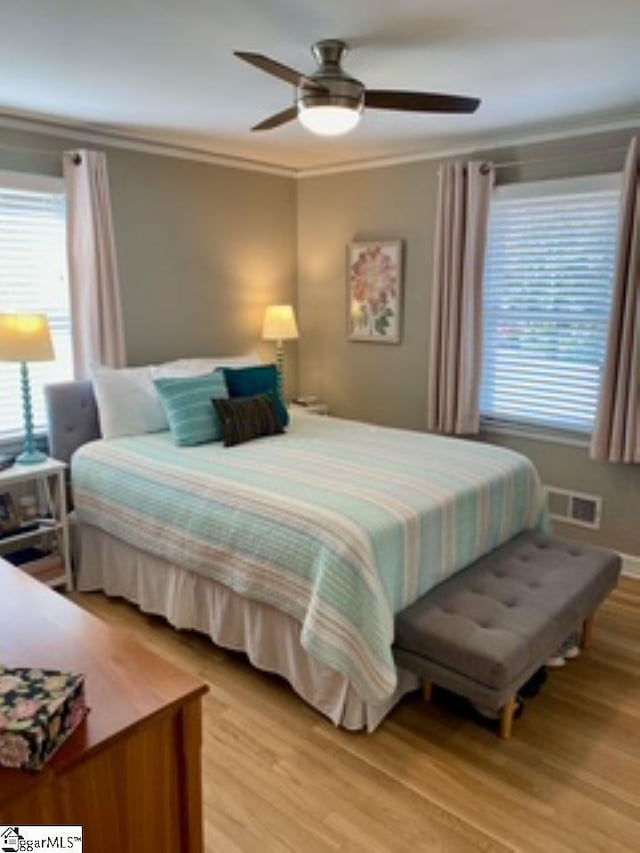 bedroom featuring ceiling fan, light wood-type flooring, and ornamental molding