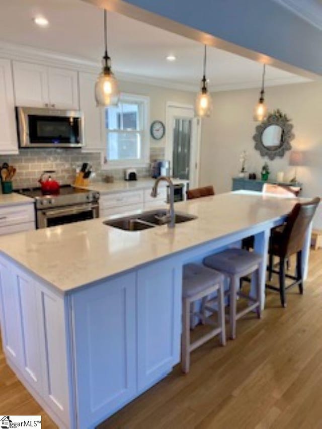 kitchen with white cabinets, hanging light fixtures, and appliances with stainless steel finishes