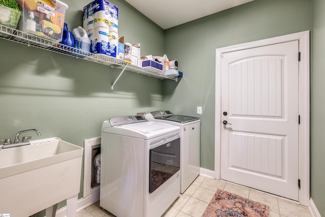 clothes washing area featuring light tile patterned floors, washer and clothes dryer, and sink