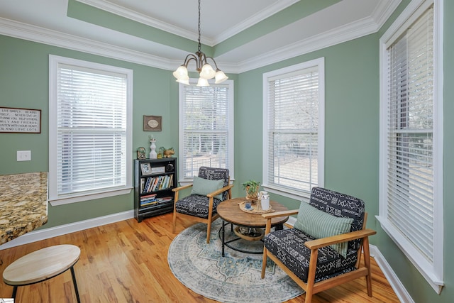 sitting room featuring wood-type flooring, crown molding, a wealth of natural light, and an inviting chandelier