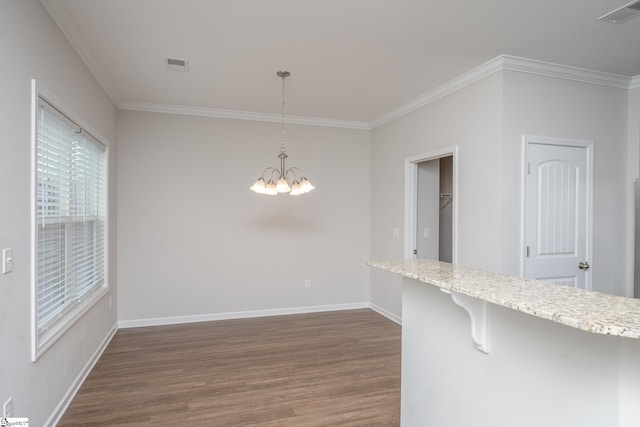 unfurnished dining area featuring dark wood-type flooring, an inviting chandelier, and crown molding