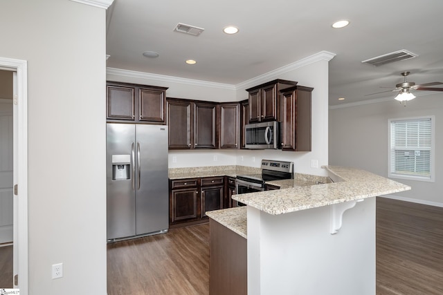 kitchen with kitchen peninsula, dark hardwood / wood-style floors, stainless steel appliances, a breakfast bar, and crown molding