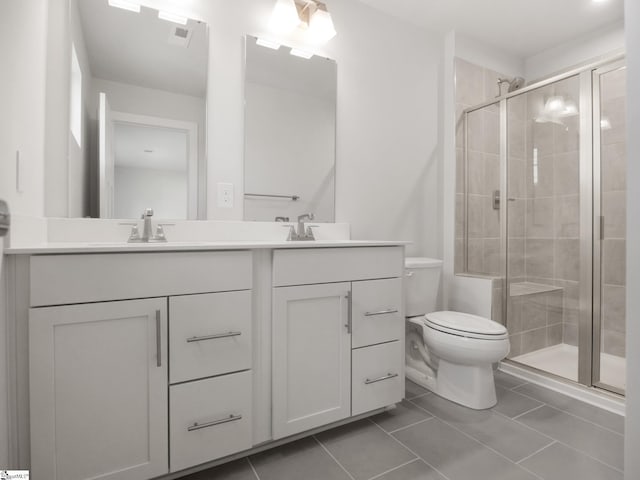 bathroom featuring tile patterned flooring, vanity, toilet, and a shower with door