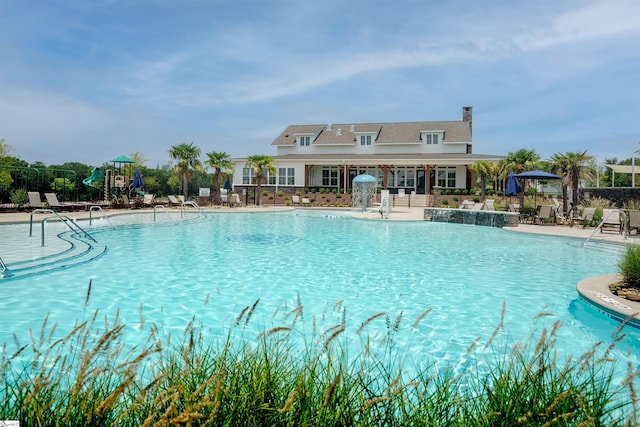 view of swimming pool featuring pool water feature, a patio area, and a playground