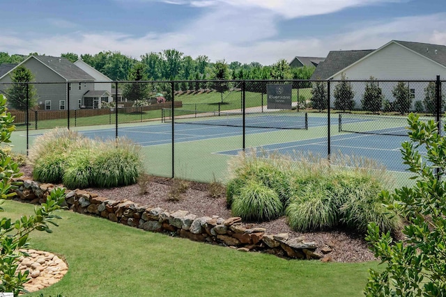 view of tennis court with a yard