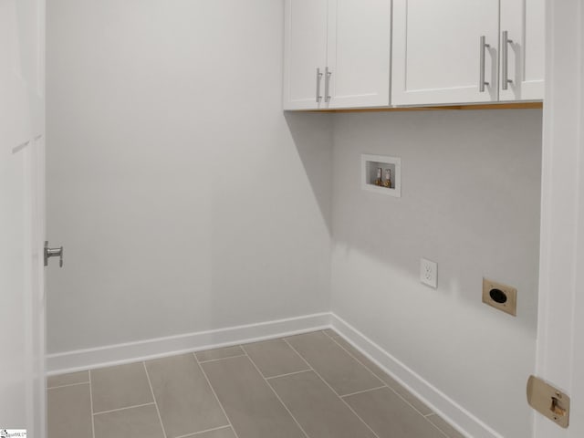 laundry area featuring hookup for an electric dryer, cabinets, dark tile patterned floors, and washer hookup