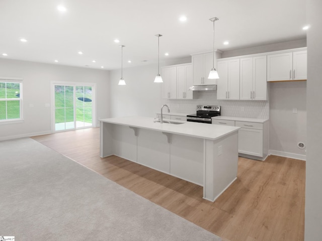 kitchen with pendant lighting, a kitchen island with sink, electric stove, light hardwood / wood-style floors, and white cabinetry