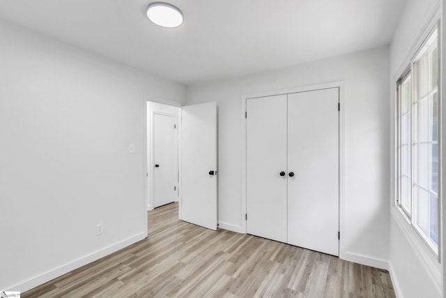 unfurnished bedroom with light wood-type flooring and a closet