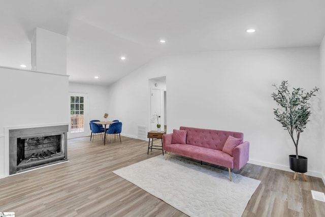 living room with light wood-type flooring and vaulted ceiling