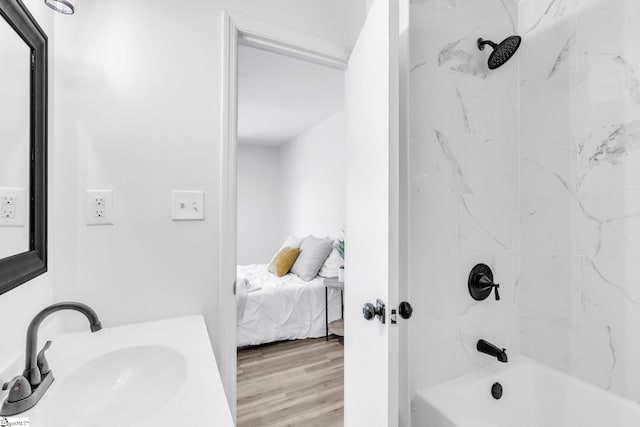 bathroom featuring wood-type flooring, tiled shower / bath, and sink