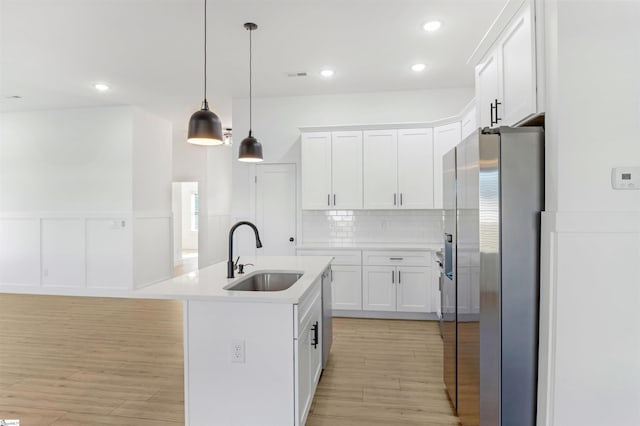 kitchen featuring stainless steel appliances, white cabinetry, a kitchen island with sink, and sink