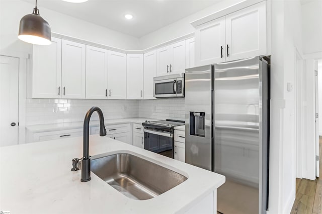 kitchen with hanging light fixtures, white cabinetry, sink, and appliances with stainless steel finishes