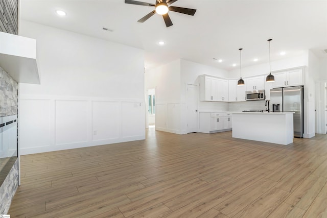 unfurnished living room with ceiling fan and light hardwood / wood-style flooring