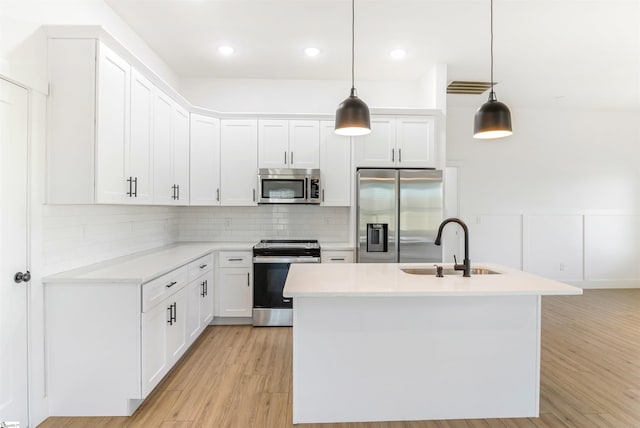 kitchen with decorative light fixtures, sink, white cabinetry, and stainless steel appliances