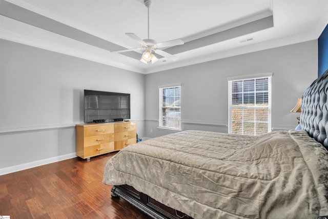 bedroom featuring dark wood-type flooring, a tray ceiling, ceiling fan, and ornamental molding