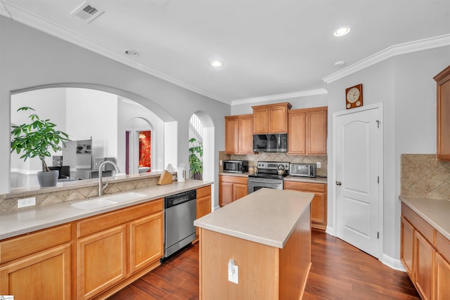 kitchen with sink, backsplash, crown molding, a kitchen island, and appliances with stainless steel finishes