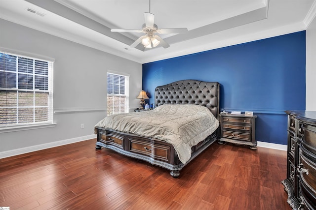 bedroom featuring dark hardwood / wood-style flooring, a raised ceiling, ceiling fan, and ornamental molding