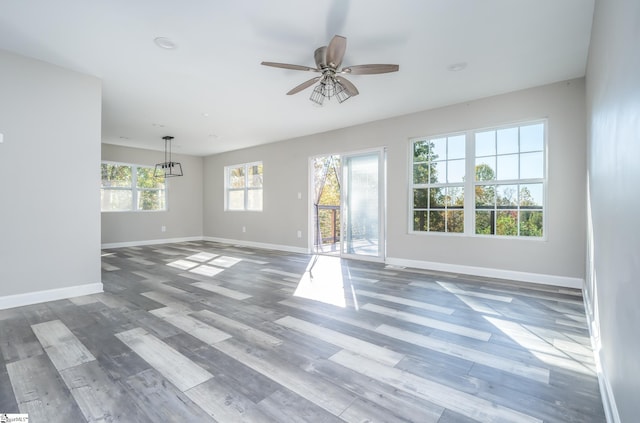 unfurnished living room with hardwood / wood-style floors and ceiling fan with notable chandelier