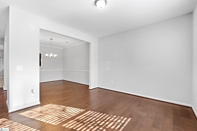 empty room with wood-type flooring, ornamental molding, and a chandelier