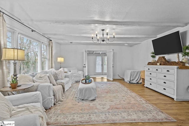 living room featuring light hardwood / wood-style floors, a textured ceiling, an inviting chandelier, and plenty of natural light