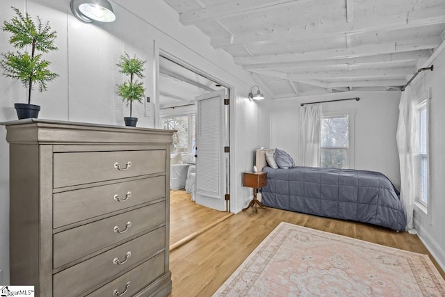 bedroom with light hardwood / wood-style flooring, lofted ceiling with beams, and multiple windows