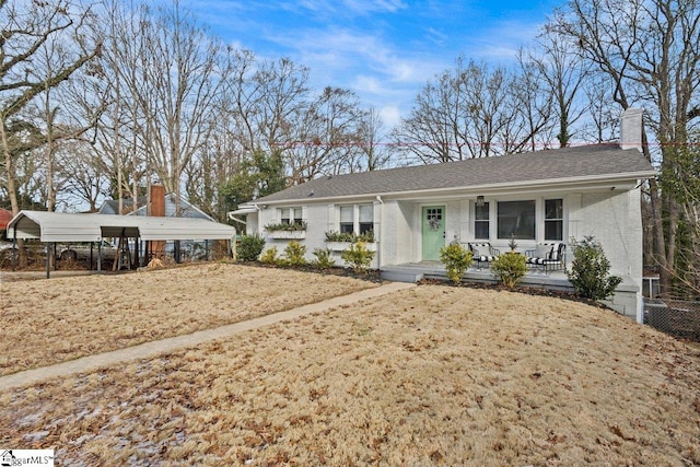 ranch-style home featuring a porch, a front yard, and a carport