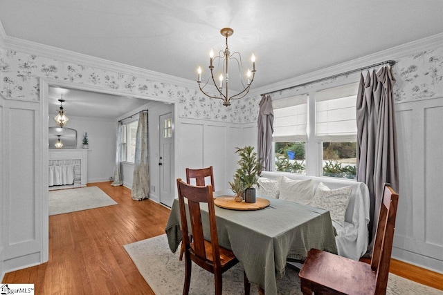 dining area with a notable chandelier, light hardwood / wood-style floors, and crown molding