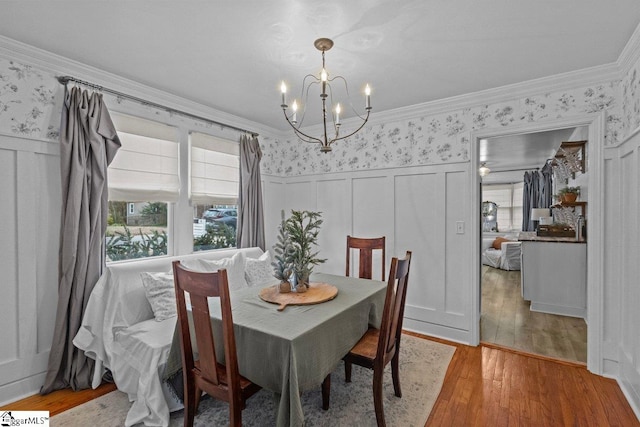 dining space with hardwood / wood-style floors, an inviting chandelier, and crown molding