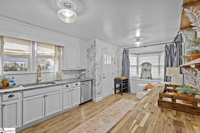 kitchen with white cabinets, tasteful backsplash, stainless steel dishwasher, and sink