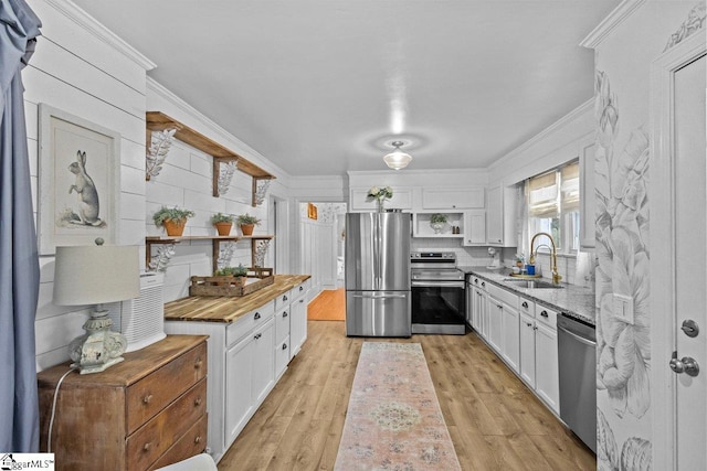 kitchen featuring white cabinets, stainless steel appliances, decorative backsplash, sink, and light hardwood / wood-style flooring